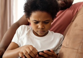 A young boy looking at a tech device.