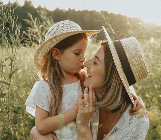 A woman and her daughter standing in a grassy field.