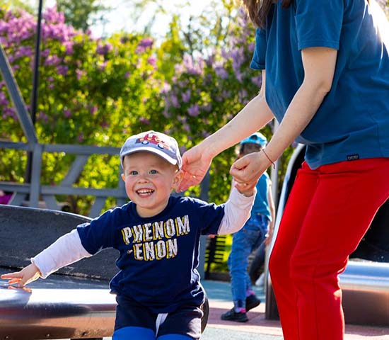 A mother and her young child enjoying a playground with slides and swings