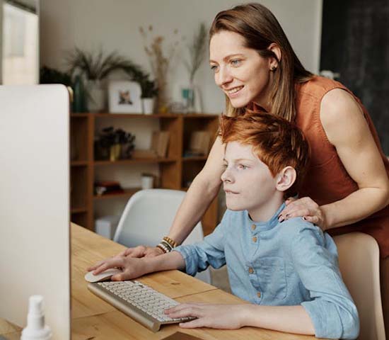 A woman and a young boy collaborating on a computer task.